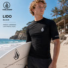 Licra de Surf Volcom Lido Black en playa surf lifestyle con tabla de surf, fotografía propia de THE SURF TOWN inspirada en sesiones de surf y protección solar en el agua