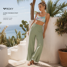 Pantalón Roxy Along The Beach Basil para mujer en fotografía lifestyle premium junto al mar con estilo beachwear relajado