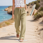 Pantalones Rip Curl AZ Classic Vetiver para mujer en una escena vacacional junto al mar, imagen editorial propia de THE SURF TOWN