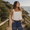 video promocional propio de the surf town de modelo vistiendo un Top Salty Crew Charter Cami Off White en un sendero litoral con vistas al mar al atardecer