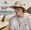 modelo llevando un gorro billabong big john lite desert durante un video propio de the surf town en la playa con olas