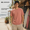 modelo vistiendo una Camiseta Quiksilver Slub Roundneck Desert Sand en un video promocional propio de the surf town en el exterior de una calle de Bali cerca del mar