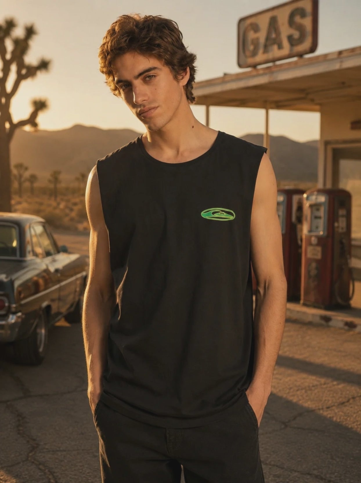 modelo vistiendo una quiksilver-camiseta-ev-quikglobe-muscle-black-hombre en un video promocional propio de the surf town en el exterior de una gasolinera vintage en el desierto