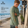 modelo vistiendo una Camiseta Rip Curl Fade Out Icons Sage Ls en un video propio editorial promocional de the surf town en un paseo maritimo junto a una tienda rip curl