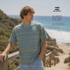 modelo vistiendo una Camiseta Billabong Paint Rack Blue Haze en un video promocional de the surf town en una pasarela de madera junto al mar
