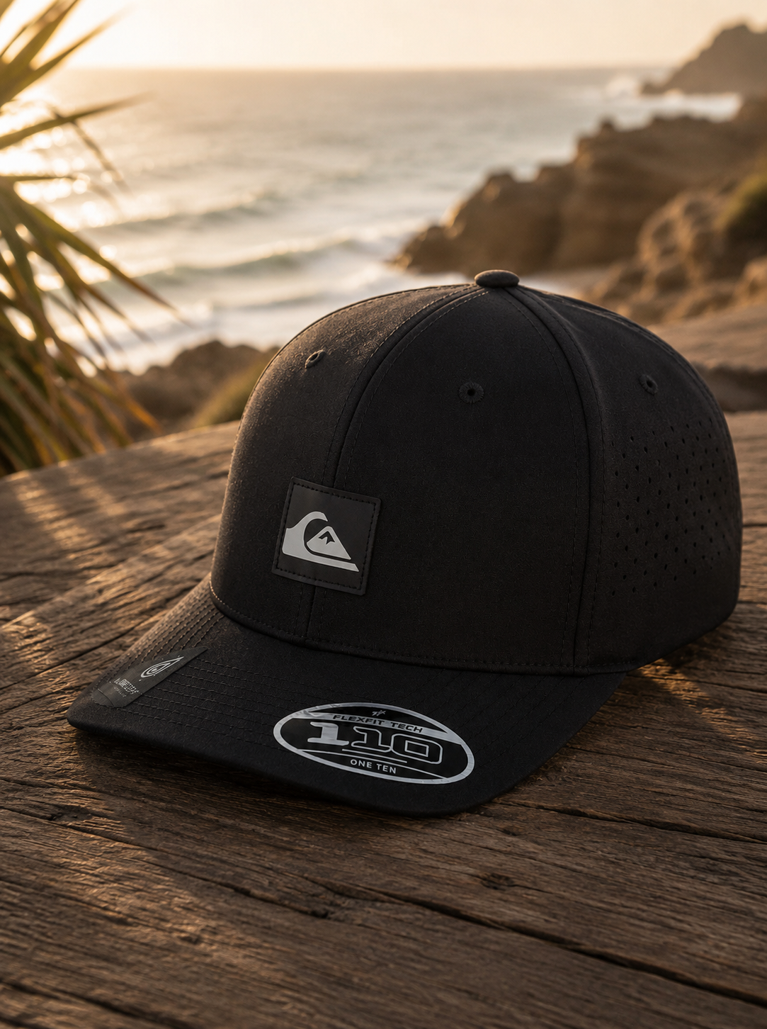 Gorra Quiksilver Adapted Black Flexfit Tech hombre estilo surf premium junto al mar al atardecer