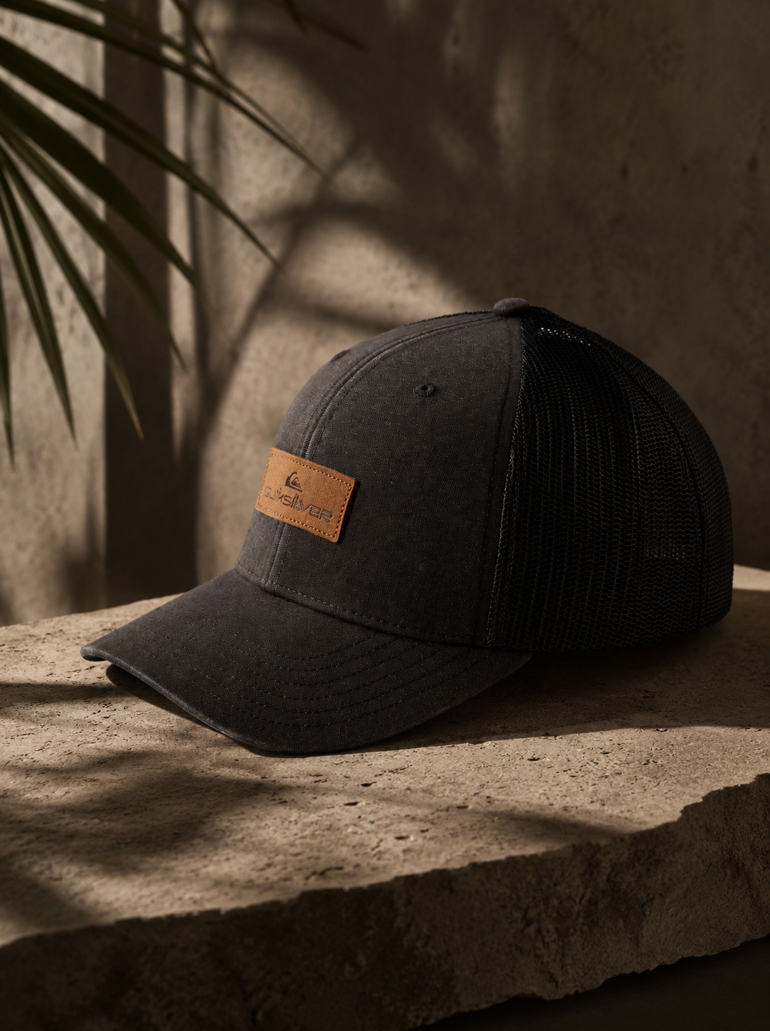 Gorra trucker Quiksilver negra Down Tech hombre estilo surf premium lifestyle sobre piedra natural tropical