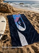 Toalla Quiksilver Freshness Nebulas Blue Fade Reflection estilo surf premium sobre arena junto al mar
