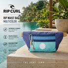 Riñonera Rip Curl Rip Waist Bag Multicolor en fotografía editorial propia de THE SURF TOWN junto a piscina infinity tropical con diseño colorido, múltiples compartimentos, correa ajustable y estilo surf lifestyle para viajes y uso diario.