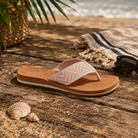 Sandalias Reef Spring Woven Cameo Rose para mujer sobre fondo lifestyle de playa con madera envejecida y accesorios surferos premium