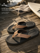 Sandalias Rip Curl Surf Revival Leather Mocha en escena surf lifestyle sobre madera junto al mar con luz natural cálida
