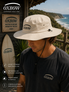 Sombrero Oxbow Ebush Dune beige hombre en escenario coastal premium con estética editorial surf cinematográfica
