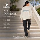 Mujer con sudadera Rip Curl Neon Diamond Heritage Bone mostrando el gráfico trasero, imagen editorial propia de THE SURF TOWN