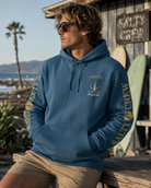 Sudadera con capucha Salty Crew azul estilo surf lifestyle premium junto a surf shack y tablas de surf en la Costa del Sol