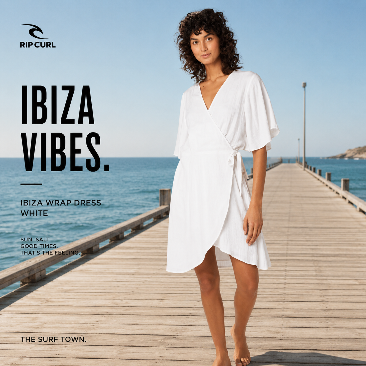 Vestido Rip Curl Ibiza Wrap Dress White en fotografía editorial propia de THE SURF TOWN sobre muelle premium junto al mar con estilo beach lifestyle exclusivo