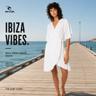 Vestido Rip Curl Ibiza Wrap Dress White en fotografía editorial propia de THE SURF TOWN sobre muelle premium junto al mar con estilo beach lifestyle exclusivo
