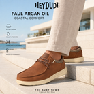 Hombre con Zapatillas HEYDUDE Paul Argan Oil en una imagen editorial propia de THE SURF TOWN junto al mar.