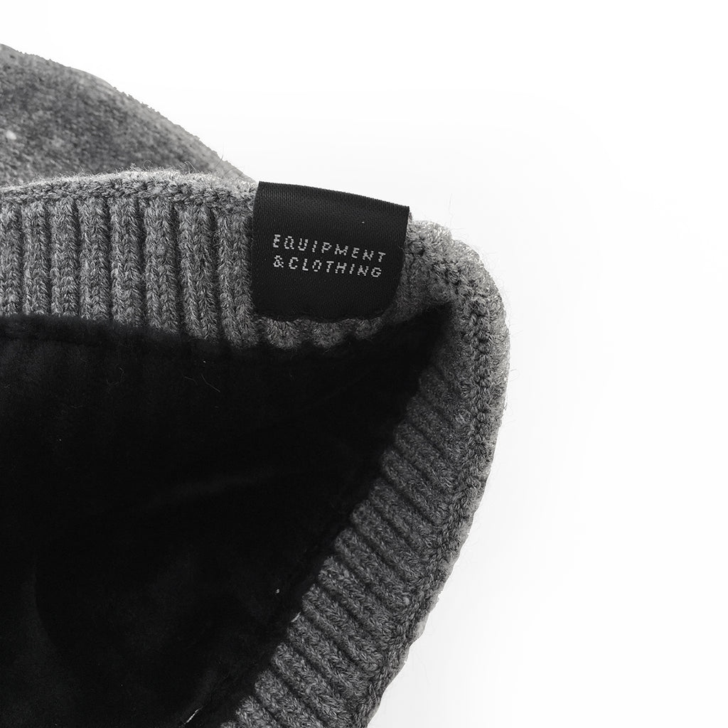 Gorro de punto elástico, de color gris claro marca The Surf Town con interior forrado de suave terciopelo y con etiqueta de la ola en el bajo.